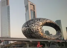 The torus-shaped Museum of the Future covered in Arabic calligraphy, with Emirates Towers behind it at dusk