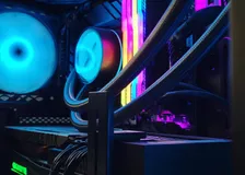 Inside of a PC case with cyan-lit fans, an AIO pump block, rainbow RGB memory sticks, and a GeForce RTX card